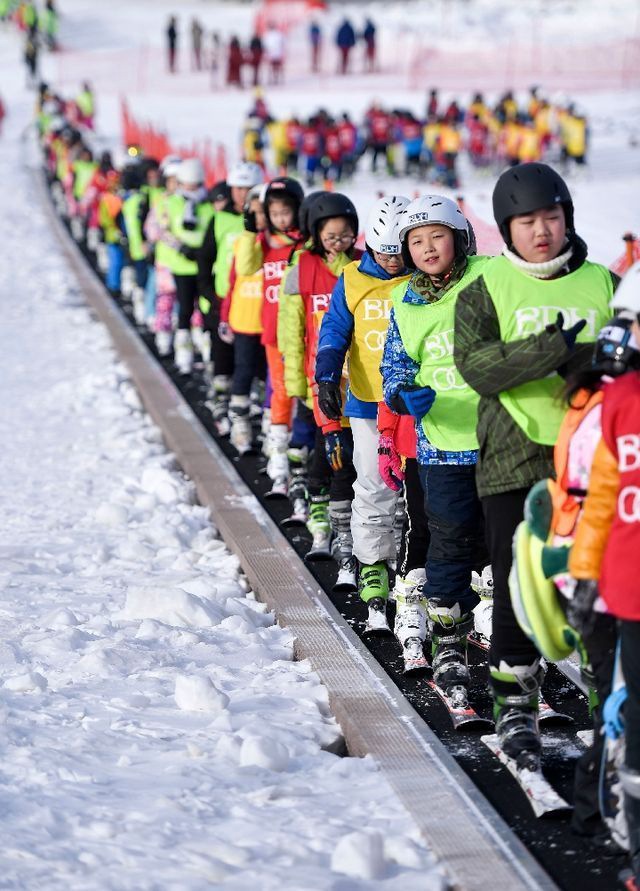 在吉林北大壺滑雪場(chǎng)，吉林市第二實(shí)驗(yàn)小學(xué)學(xué)生們?cè)诨┙叹毜膸ьI(lǐng)下乘坐“魔毯”前往雪場(chǎng)學(xué)習(xí)區(qū)域。